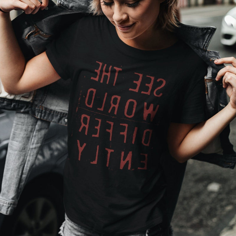 Woman Black T-shirt with reverse red letters that say See The World Differently backwards