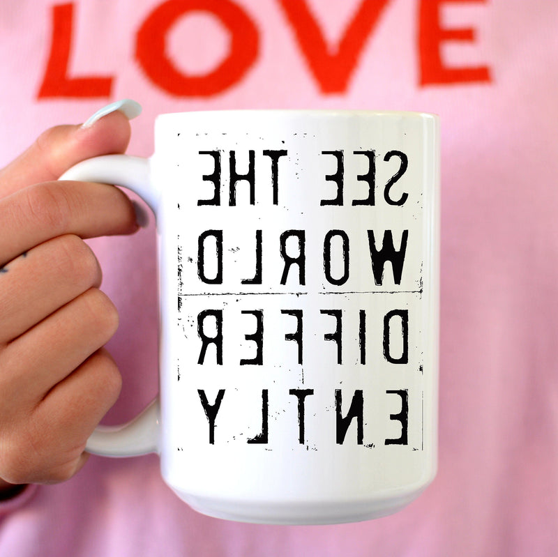 Backwords words on a mug - Woman's hand  holding Tall white mug with reverse lettering that says See The World Differently 