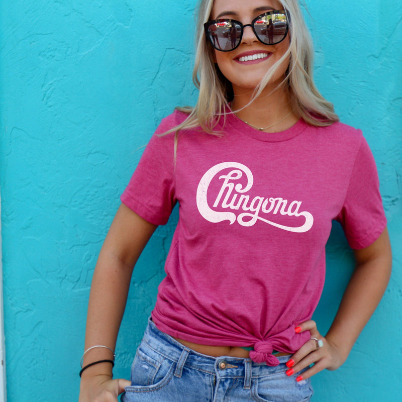 Woman wearing hot pink t-shirt with Chingona written in white cursive that looks like the Chicago logo