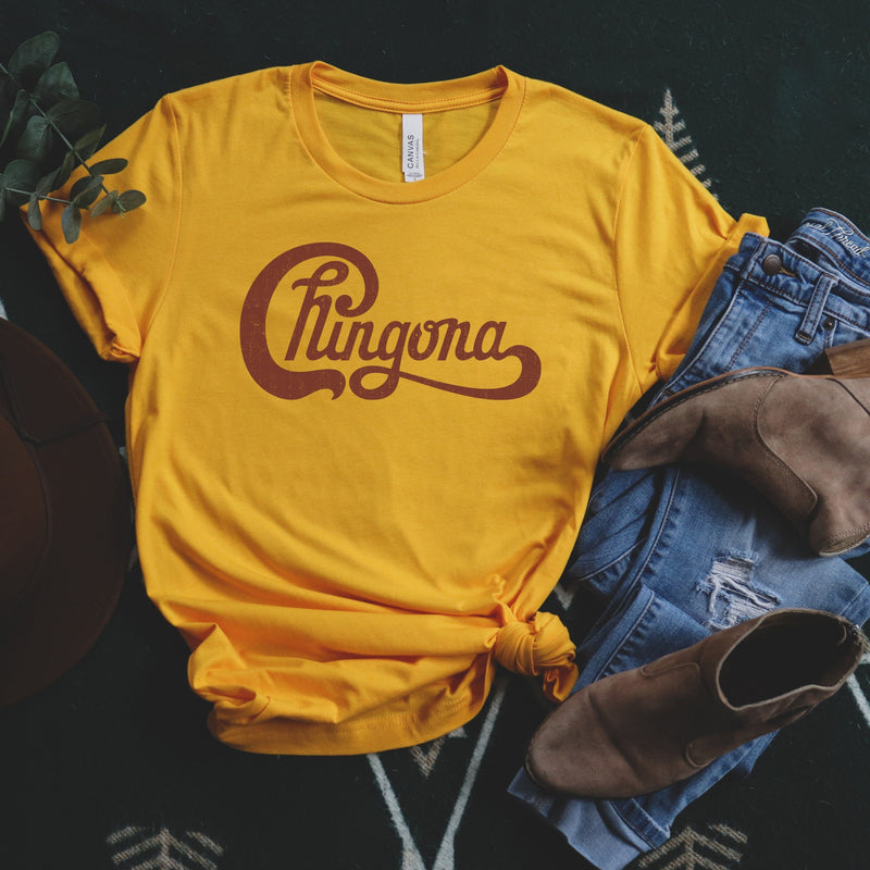 Womens yellow t-shirt with Chingona graphic in red cursive that looks like the Chicago logo