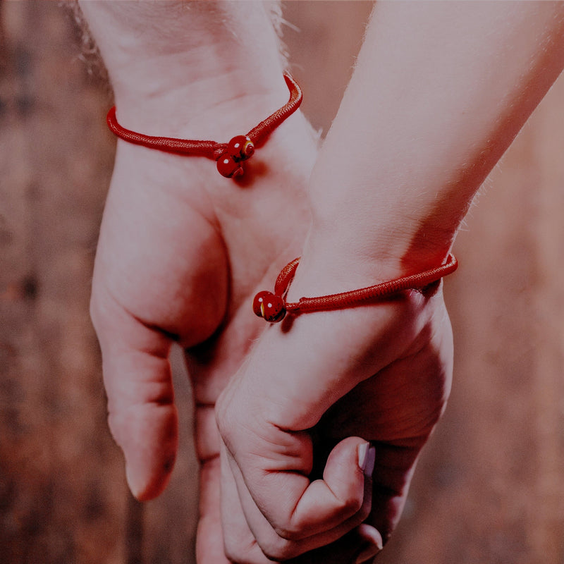 Two wrists holding hands with Authentic original hatha red string bracelets for protection to share with a friend 