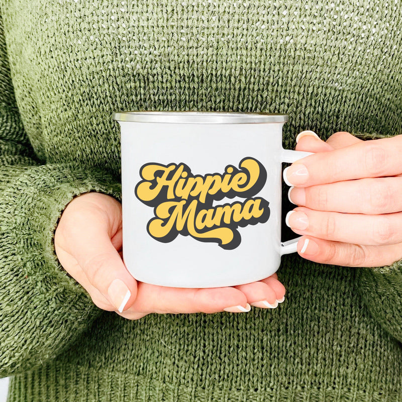 Hands holding a Silver Rimmed White Enamel Camp Mug with yellow vintage lettring that says "Hippie Mama"
