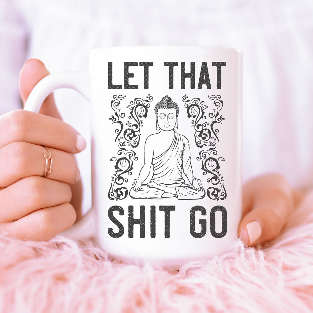 Tall white mug with meditating young Buddha and the words "Let that shit go"