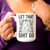 Tall white mug with meditating buddha and the message "LET THAT SHIT GO"