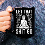 Woman's hand holding tall black coffee mug with white Let That Shit go and  meditating buddha graphic 