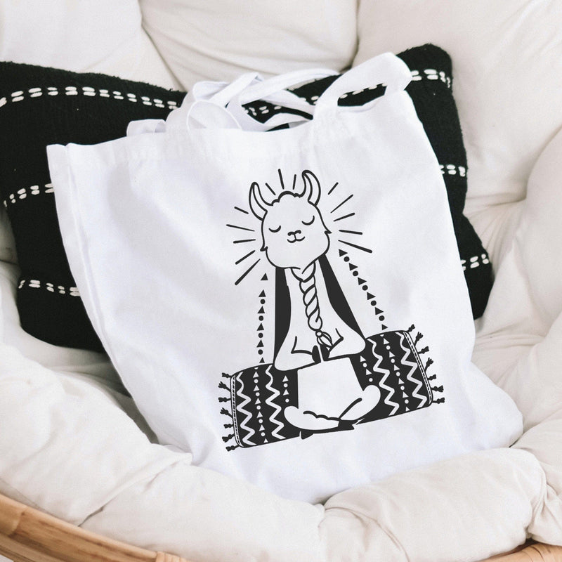 White canvas tote bag with black graphic of a meditating llama doing yoga