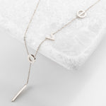 Silver lariat necklace with lowercase latters spelling "love"