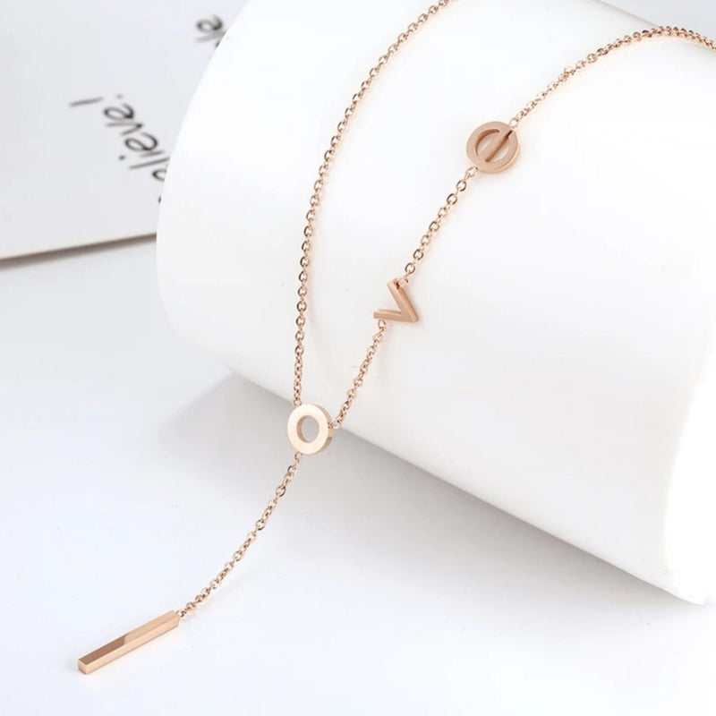Rose Gold lariat necklace with lowercase letters spelling "love" with the letter "l" hanging down the center