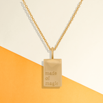 Womens gold tag necklace with rectangle charm that says "made of magic"