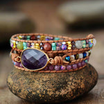 3 layer leather and gemstone boho wrap bracelet with large Amethyst centerpiece and Lepidolite accents - bracelet sitting on a rock
