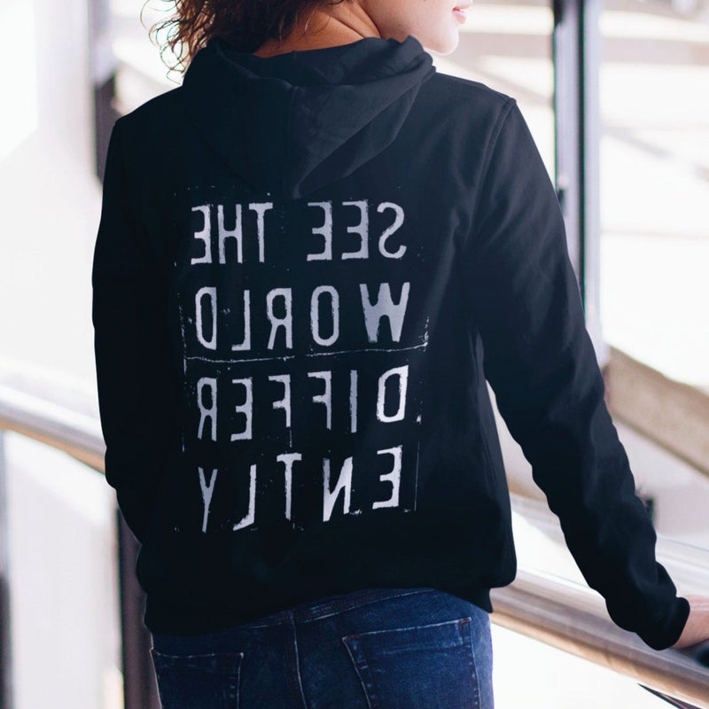 Woman wearing black hooded sweatshirt with the words 'See The World Differently' printed backwards on the back in reverse white lettering