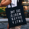 Black tote bag with backwards words "SEE THE WORLD DIFFERENTLY"