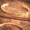 Gold reverse cuff bracelet that says the words SEE THE WORLD DIFFERENTLY backwards 