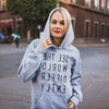 Heather gray hooded sweatshirt with reverse black letters that say See The World Differently backwards