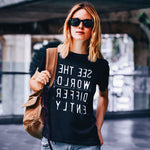 Woman wearing Black T-shirt with reverse white letters that say See The World Differently backwards