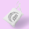 White boho canvas tote bag that says 'Stay Wild Moon Child' with black crescent moon made of flowers