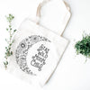 White canvas tote bag that says 'Stay Wild Moon Child' with black crescent moon made of flowers